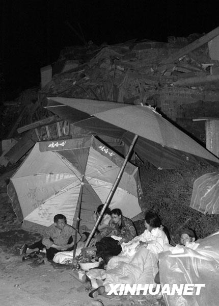 2008年5月13日凌晨，绵竹市汉旺镇的一些居民露宿在垮塌的建筑前。