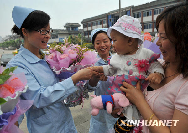 5月11日，“地震宝宝”代无极（左三）和护士王丽阿姨（左一）握手，她的妈妈（右一）今天特地为三位护士每人送上了一束鲜花。